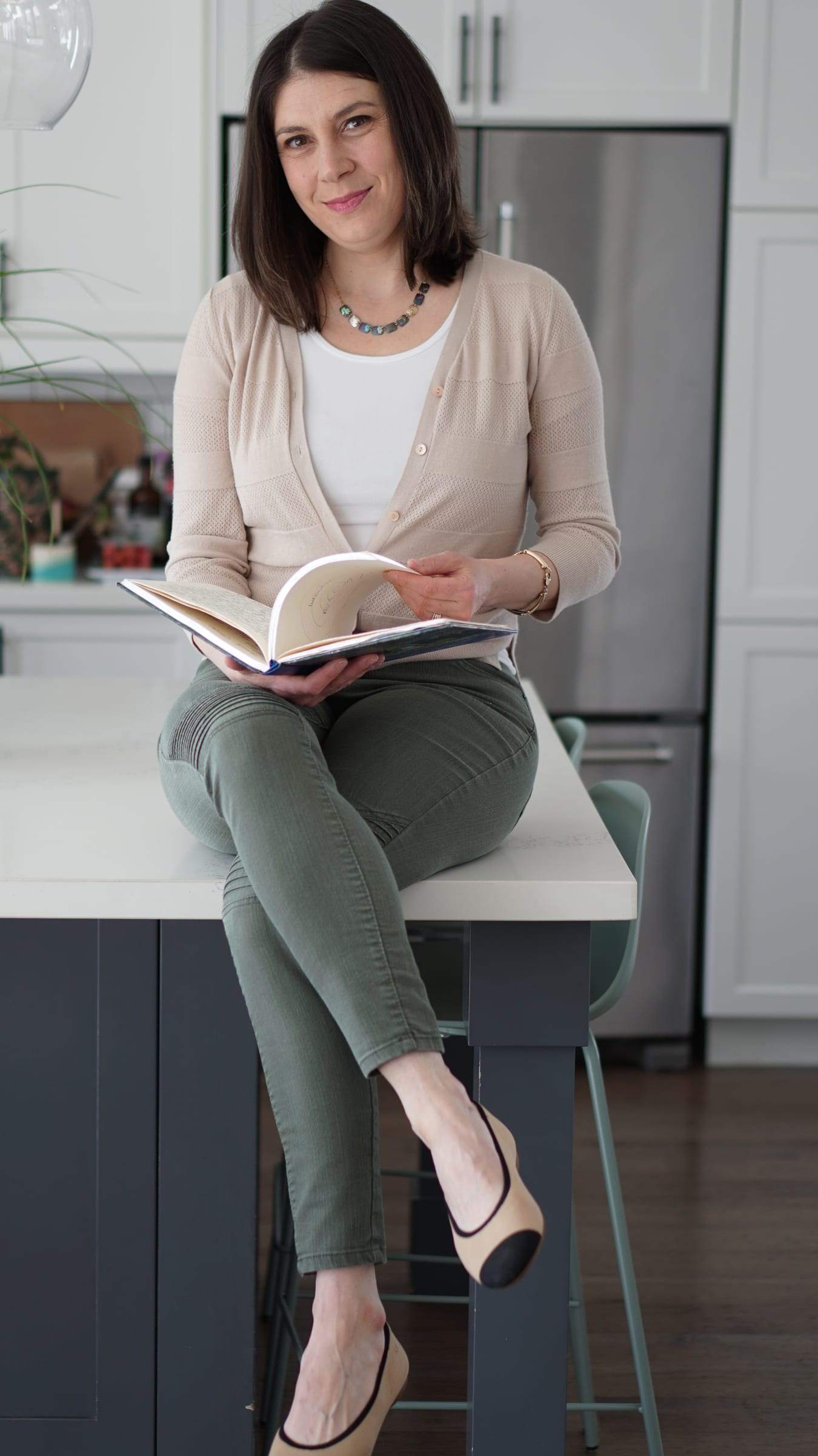 Sydney Blum sitting with an open journal in a bright kitchen.
